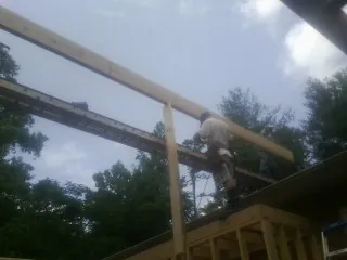 Carpenter setting a ridge beam over a new addition frame — Ice Dam Removal by Roofing Brothers in Geneva